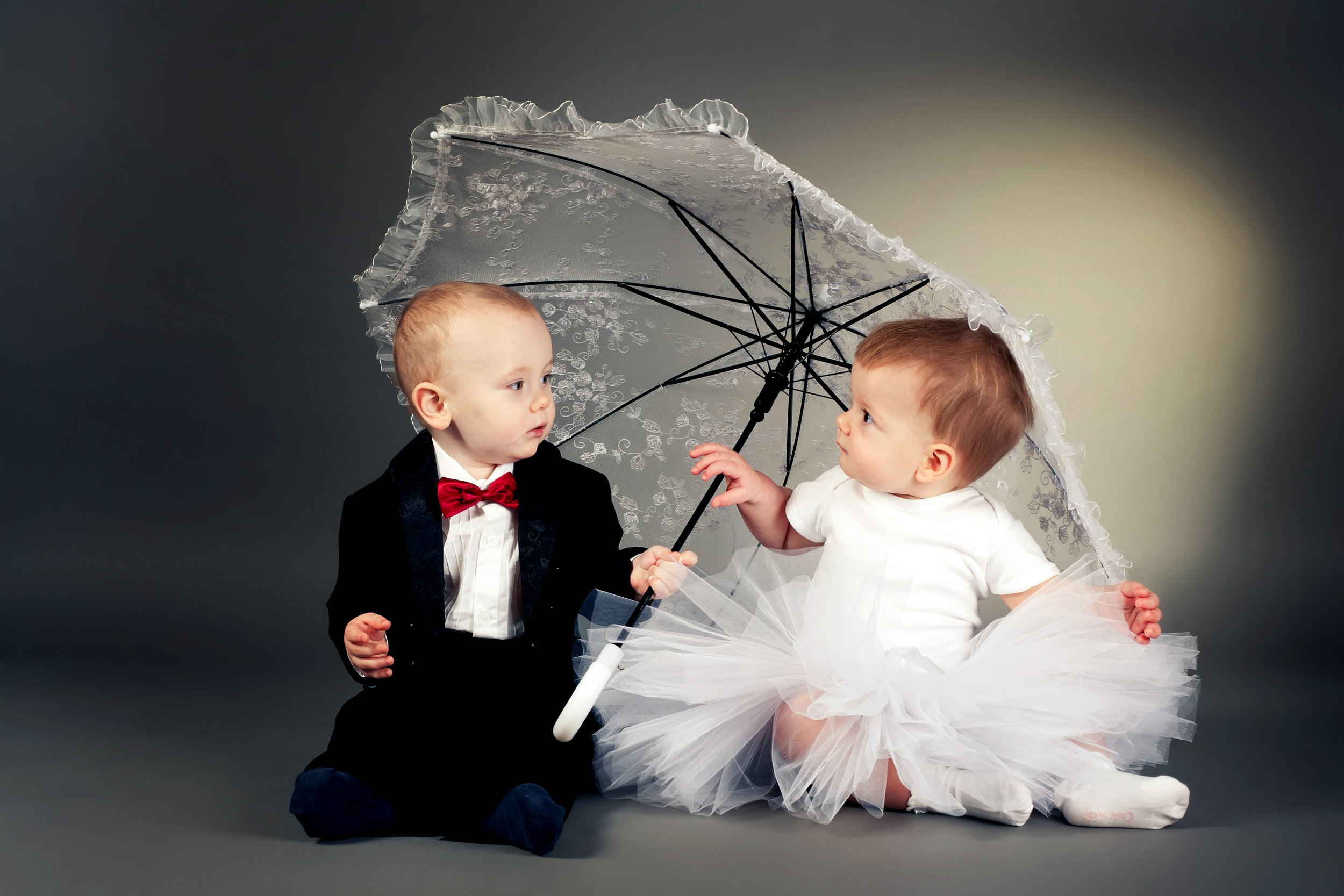 Little bride and groom sitting under an umbrella