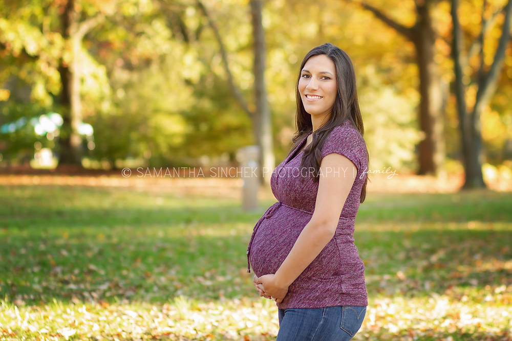 mother to be holds her belly during a beautiful fall maternity session in cincinnati ohio