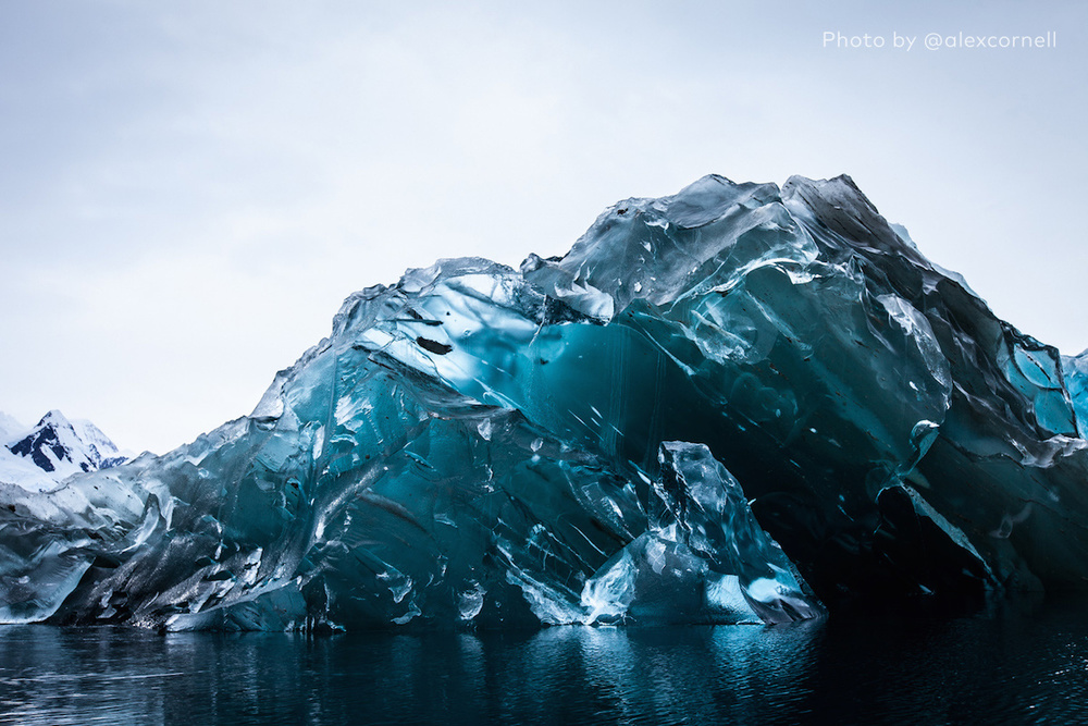 A glassy blue iceberg, free of snow.