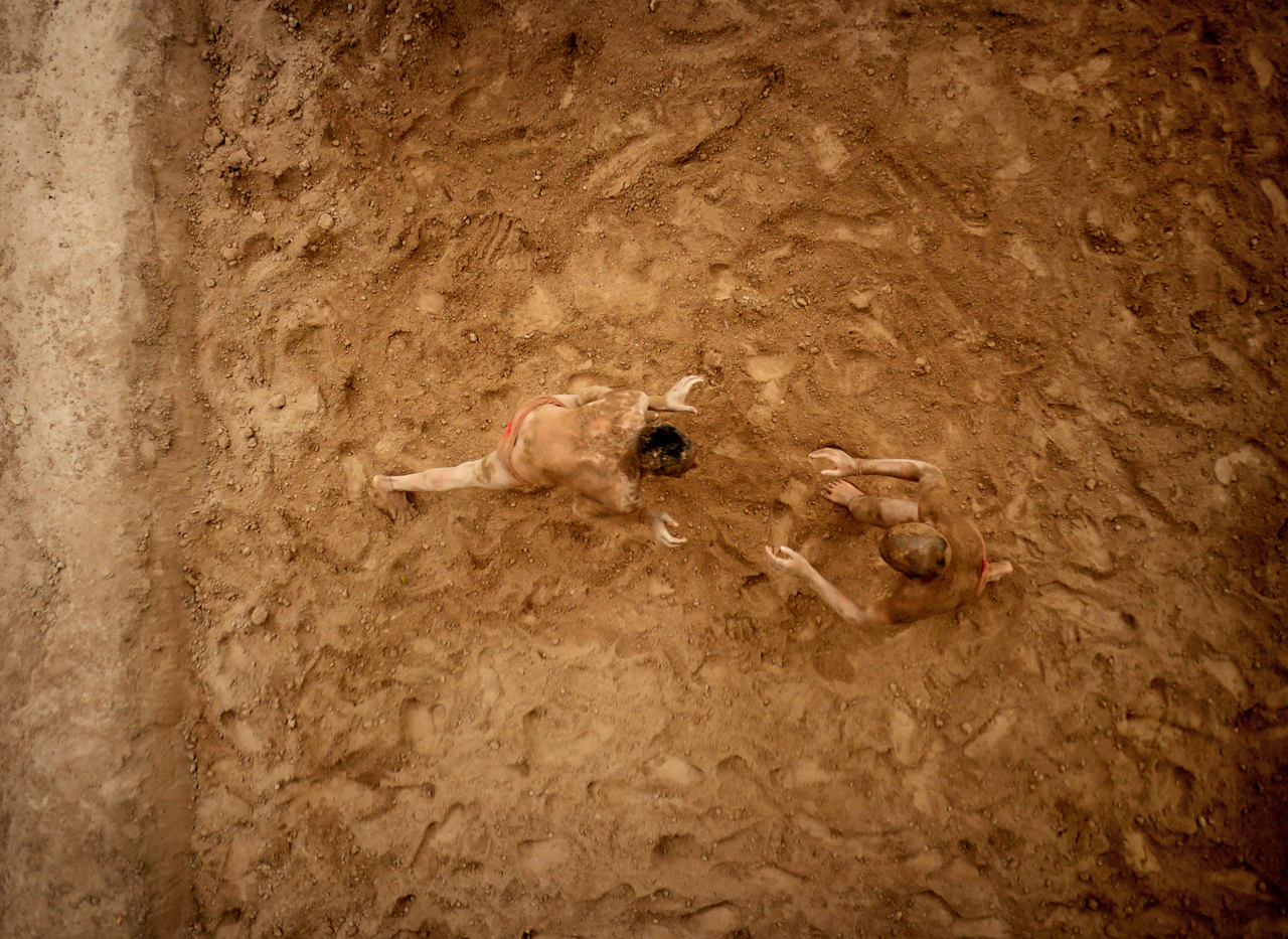   Two wrestlers practising the ancient Indian sport of Kushti in a pit they had hacked into the ground two hours earlier.   
