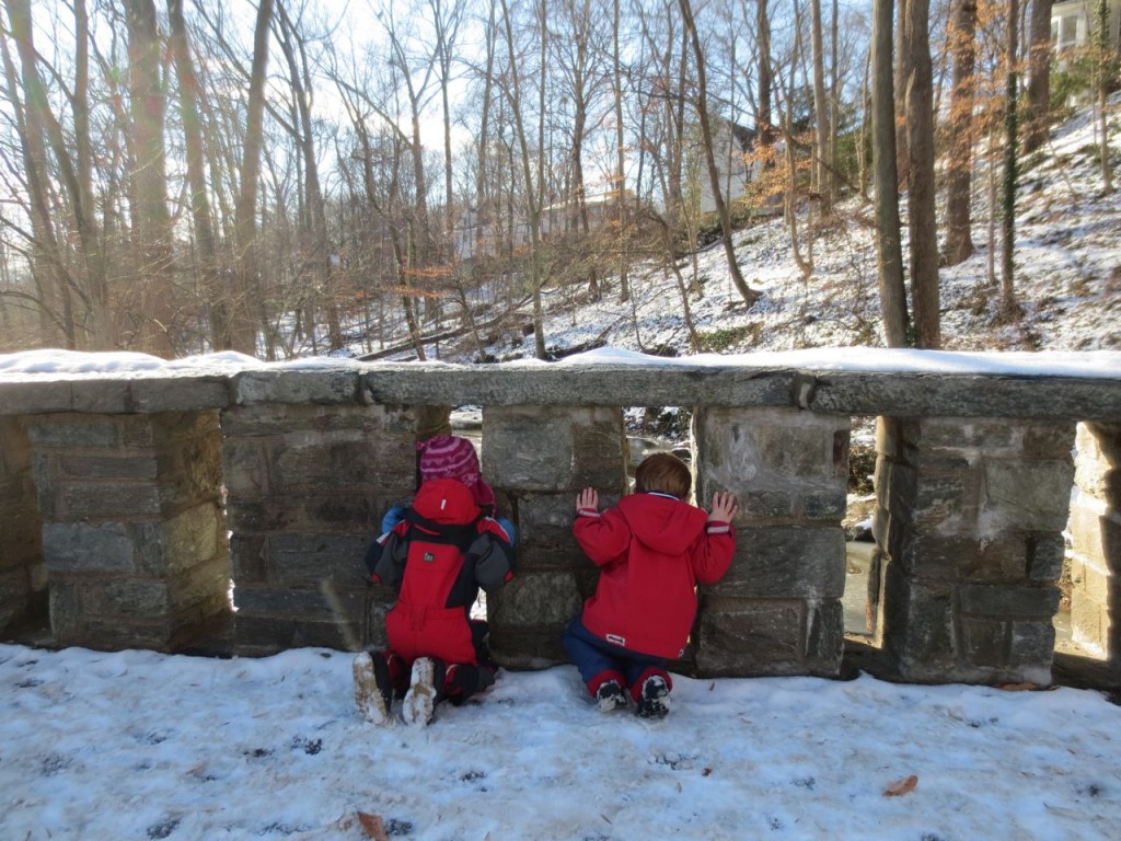 Children stop and look through the pillars of the stone bridge.