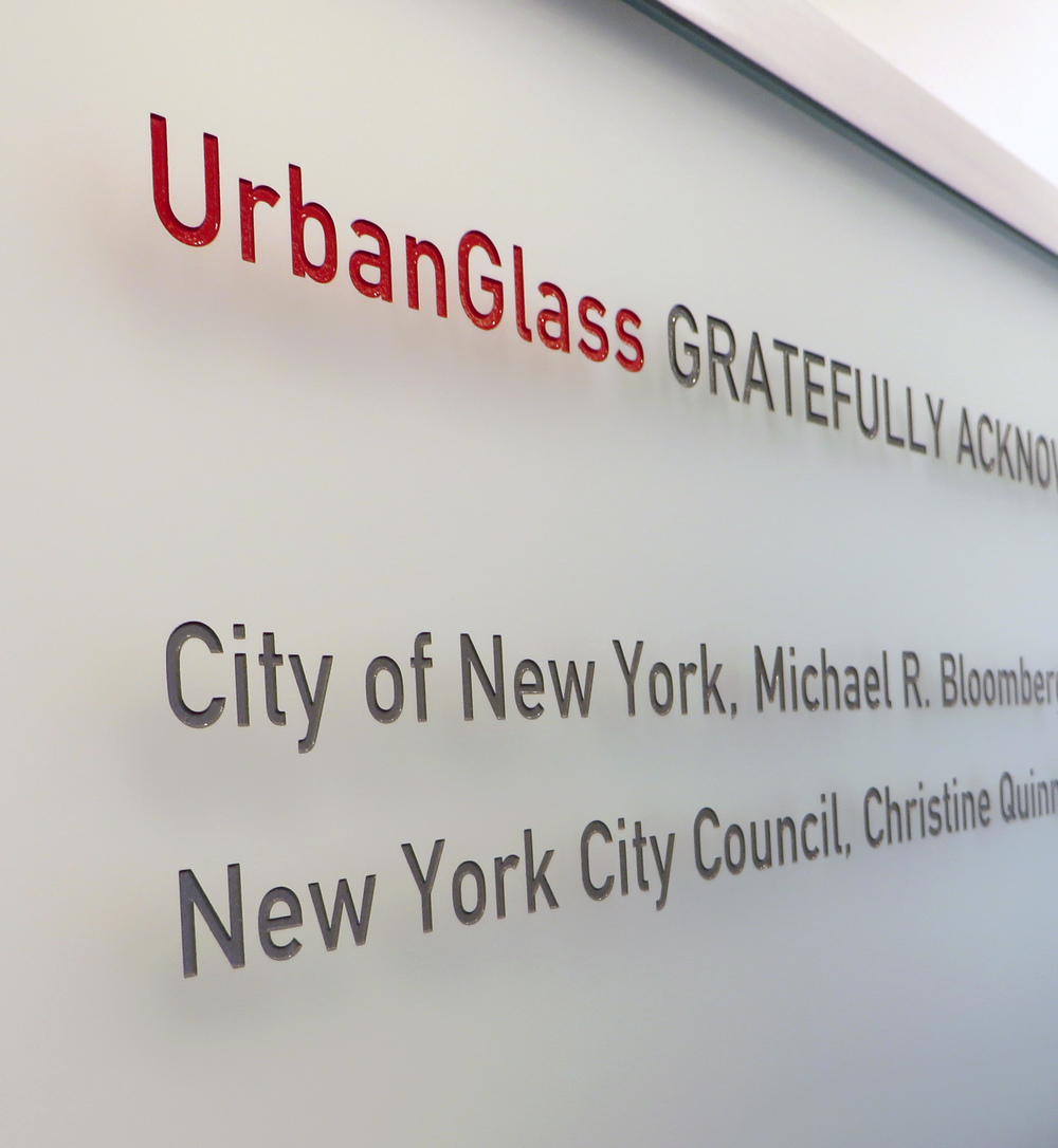 Custom sandblasted glass donor wall with carved and infilled text and gradient frosted etch finish.
