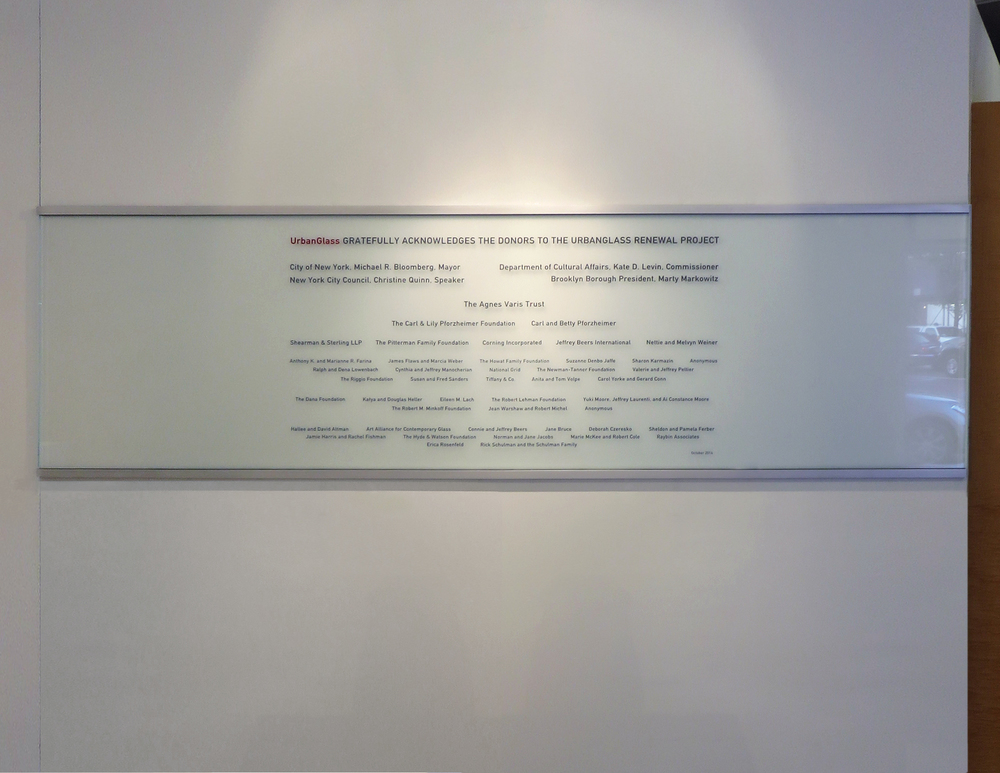 Custom sandblasted glass donor wall with carved and infilled text and gradient frosted etch finish.