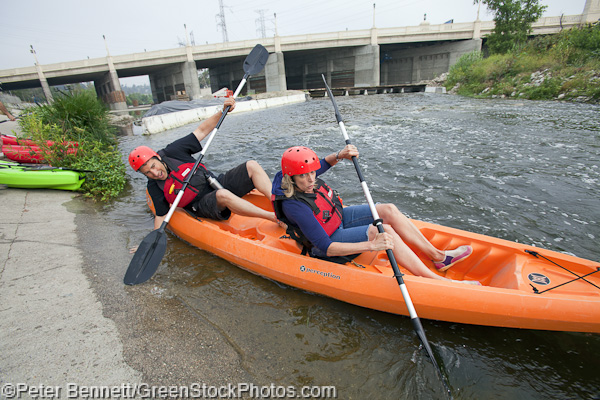 A couple launches their kayak from the banks of the LA River along the Glendale Narrows section, a soft-bottomed section of the river.