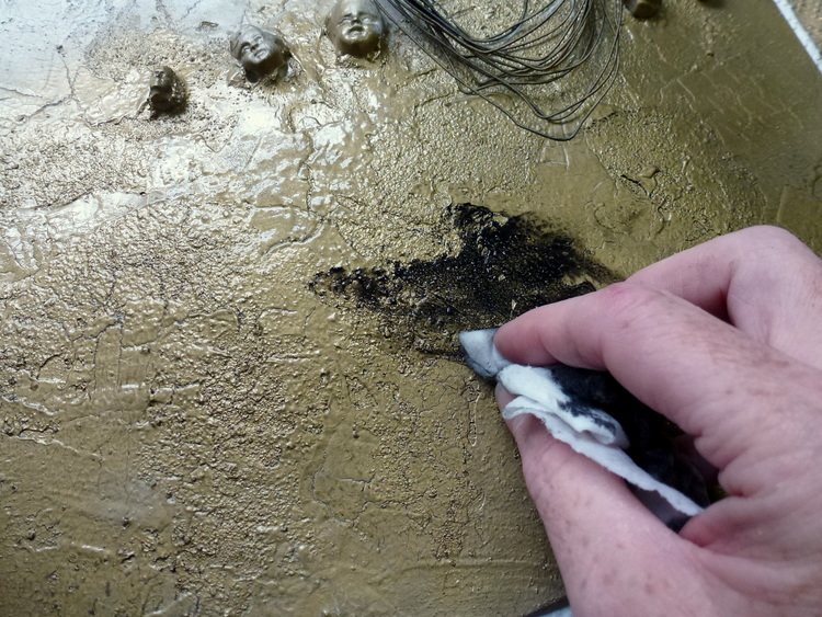 To highlight the texture of the sand and crackle medium apply some heavy black gesso using a moist baby wipe; rub into cracks and depressions and then buff off excess.