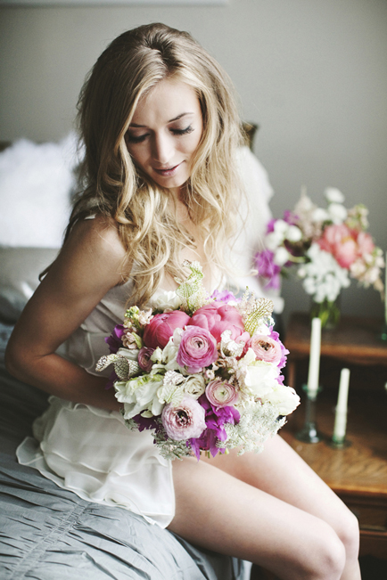 Bride with floral bouquet on bed