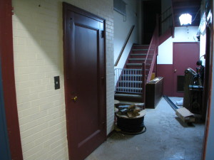 The elevator is the door at the left. The stairs ahead have a more than usual steep pitch. 