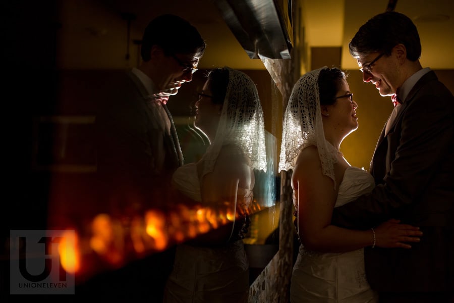 Bride and groom sharing an embrace in front of fireplace in Ottawa hotel lobby