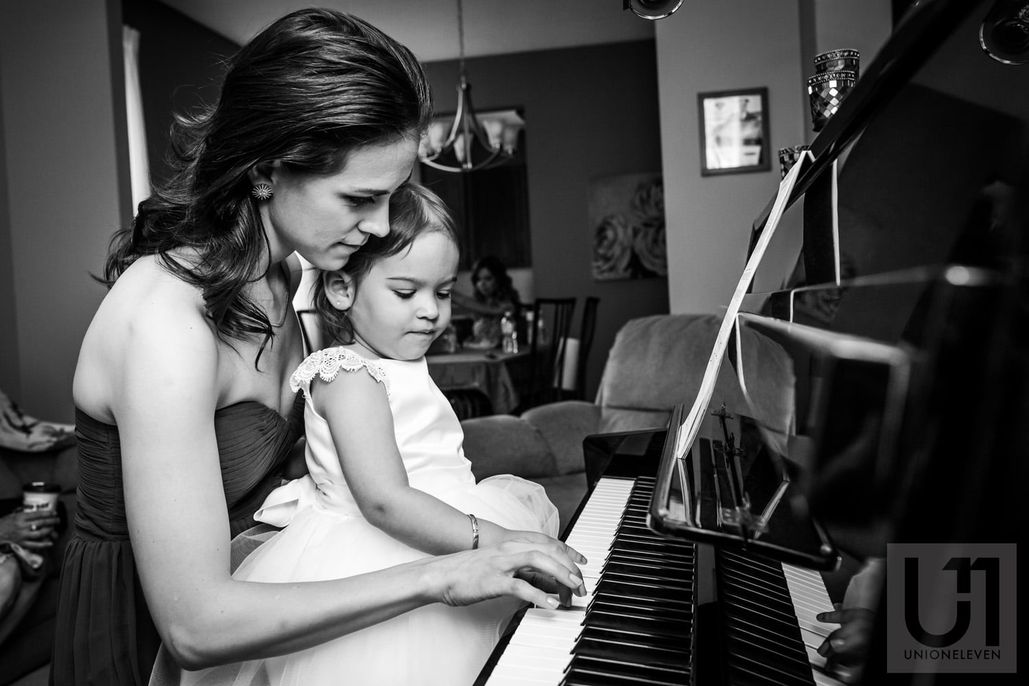 bridesmaid playing piano with young girl during getting ready portion of wedding day in Ottawa