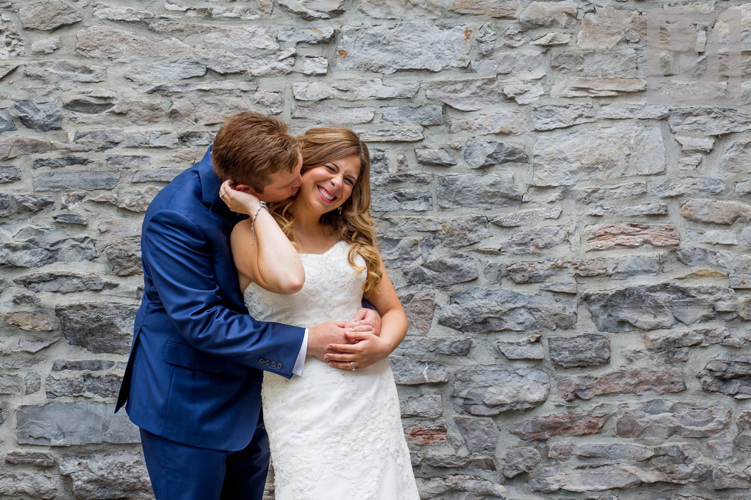 groom kissing bride's neck against brick wall in Byward market, Ottawa while she giggles 