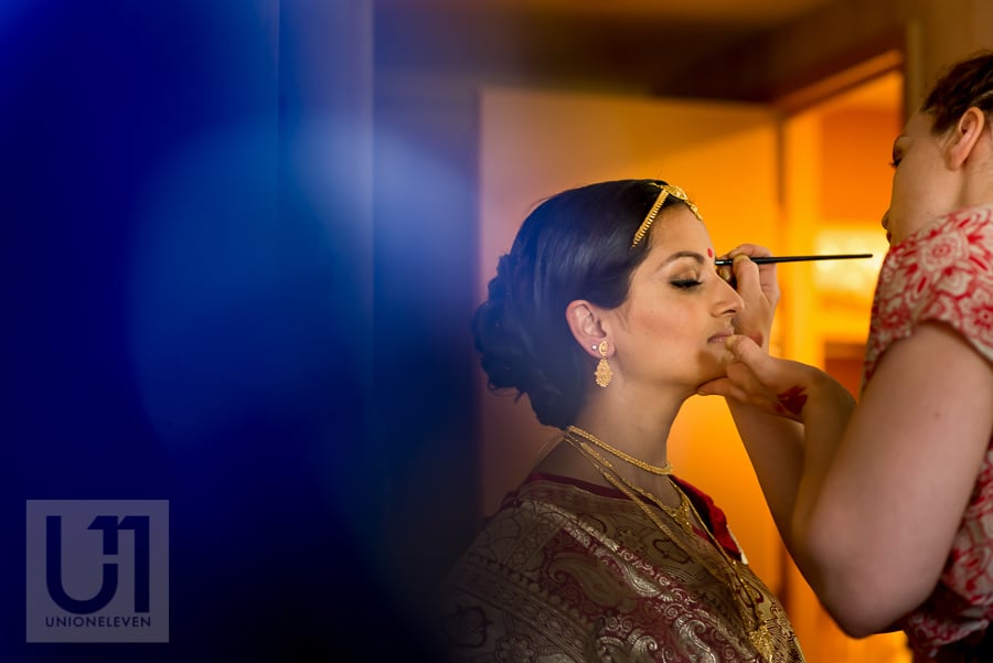 Hindu bride in traditional dress having her make up done
