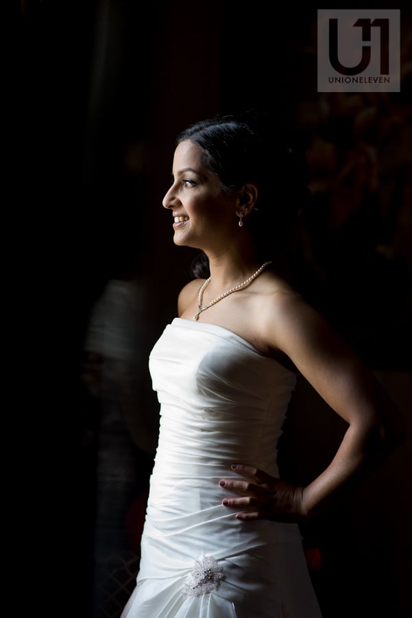 portrait of bride standing in front of window in her wedding gown
