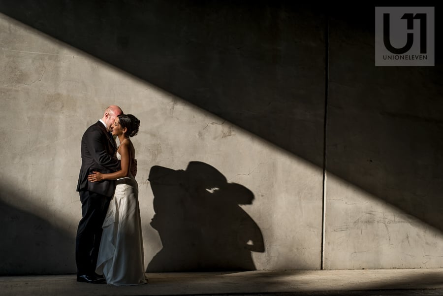 portrait of bride and groom against concrete wall with strong directional light, in downtown Ottawa