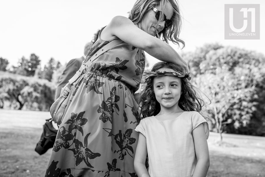 Flower girl having a flower crown adjusted on her head by woman.