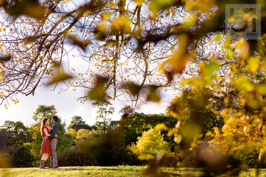 young couple standing in an embrace at the Arboretum, facing each other, with tree branches in the foreground