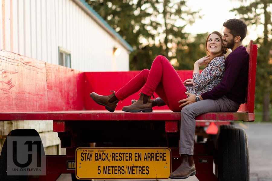 young couple sitting in an embrace on a red wagon at the Arboretum in Ottawa