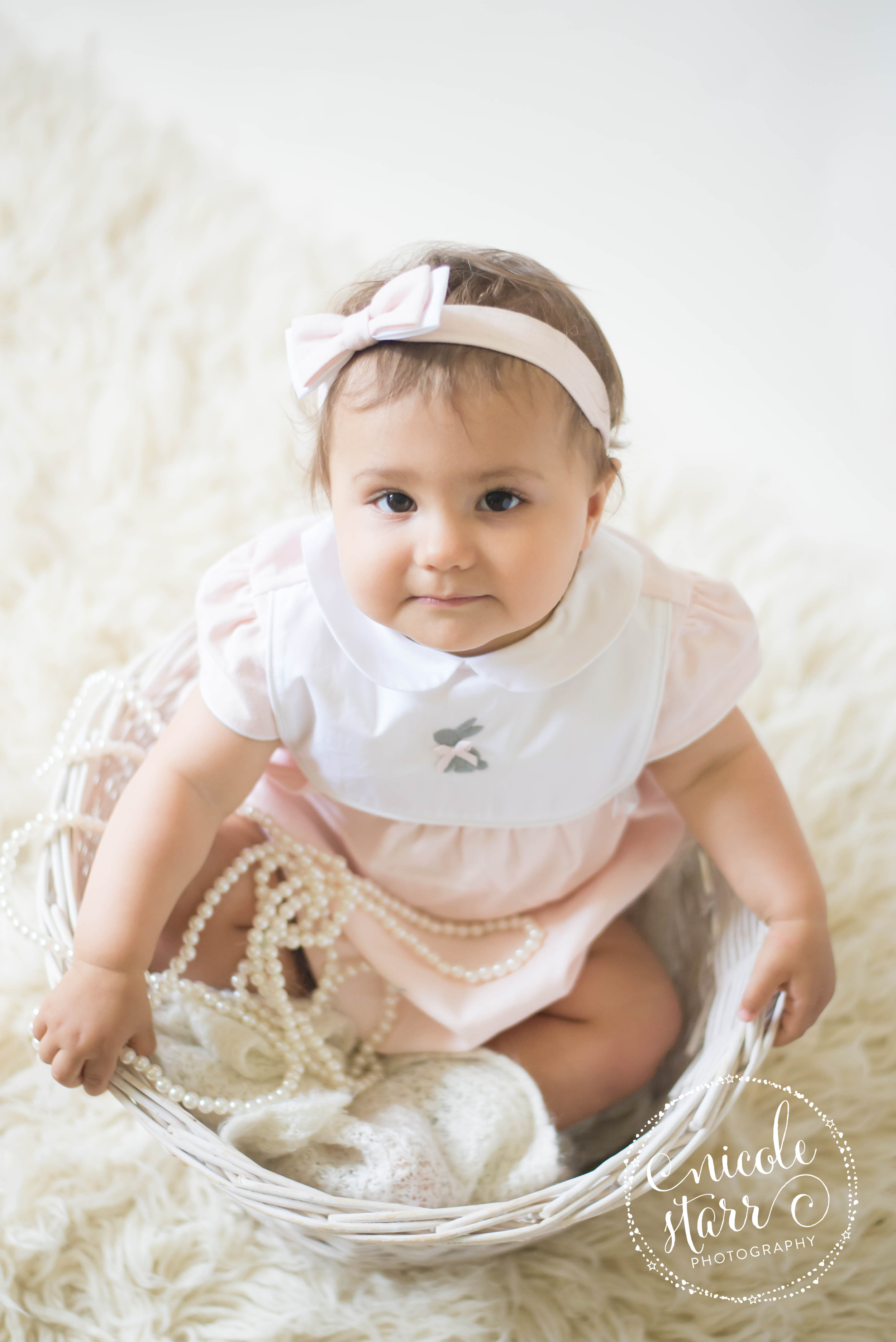 baby in a basket with pearls and a pink bunny dress