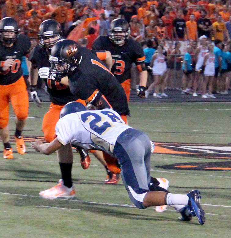 ROSS MARTIN/Citizen Photo Platte County quarterback Justin Mitchell lowers his shoulder in an attempt to gain more yards while William Chrisman’s Kyron Mason  (28) tries to make the stop Friday Aug. 20 at Pirate Stadium.