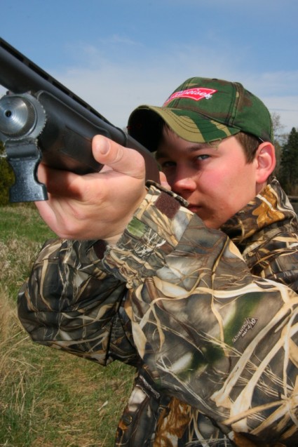 Senior portrait Luke aiming his shotgun