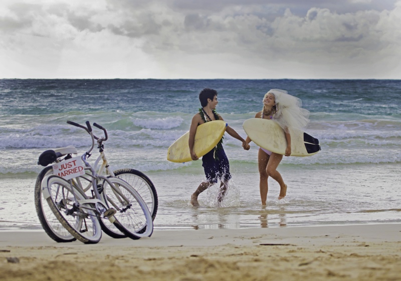 newlywed couple at the beach with surfboards and bikes