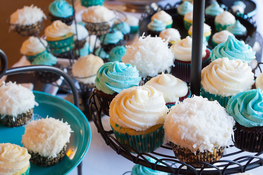 Several cupcakes on a serving table at a wedding ceremony and reception. The colors here are black, blue, and white.