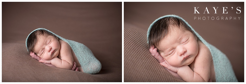 newborn in a wrap, blue, toes touching chin