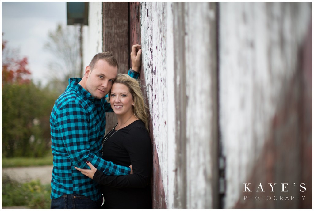 couple cuddling by barn, engagement, heart