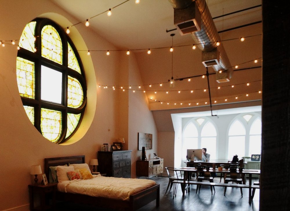 an original stained glass window overlooks a custom Unruh bed
