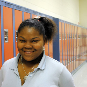 Female student smiling in front of lockers