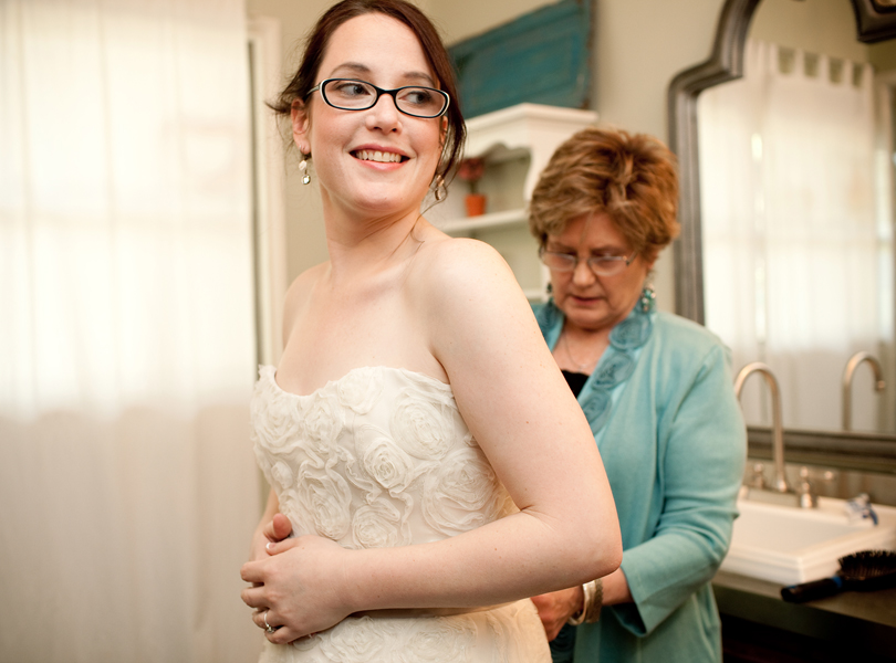 mother of the bride zipping brides dress photograph
