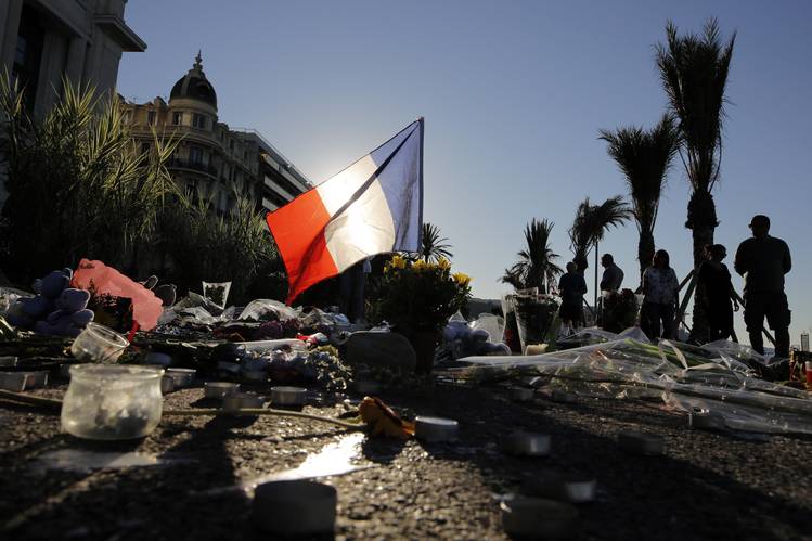 A French flag stands stall among a floral tribute for the victims killed..
