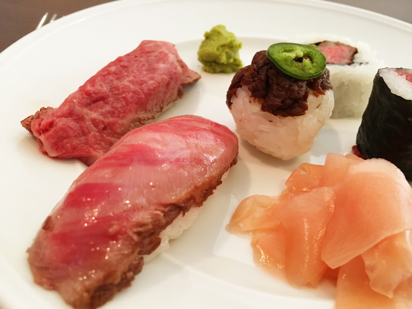 Matsusaka beef sushi platter, clockwise from the shiny on the front left: New York Strip tataki nigiri, flash-seared filet sushi roll, raw filet maki roll, spicy tuna roll, round beef cooked in mirin and soy and topped with jalapeno