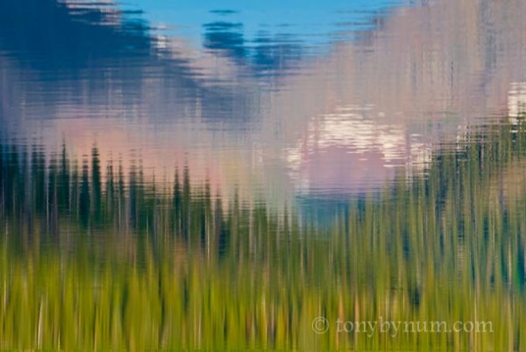 a reflection of trees, mountains and sky