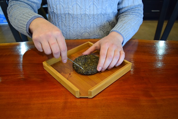 breaking off pieces of a puer before it is  brewed gongfu style