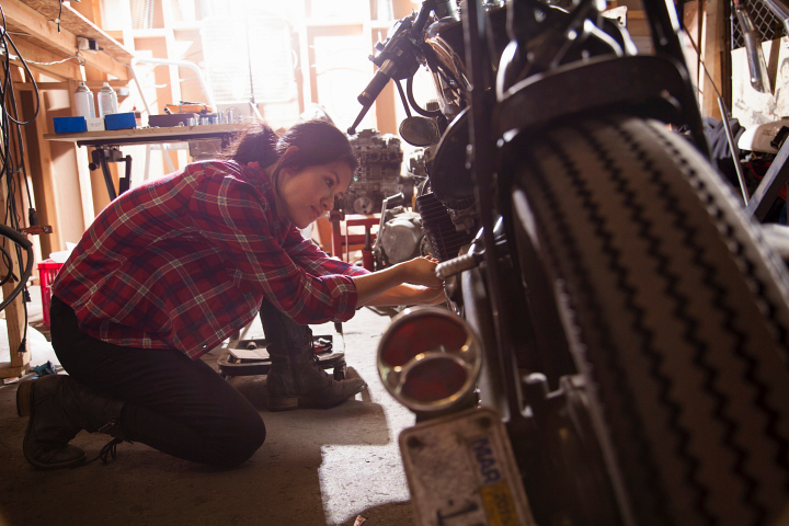 Female mechanic working on motorcycle in workshop
