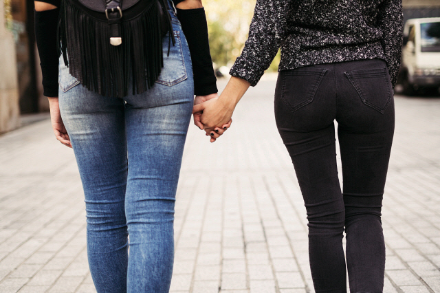 Back view of two women holding hands on the street