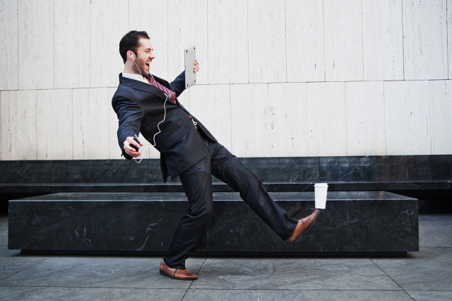 Businessman holding laptop and balancing coffee on his foot