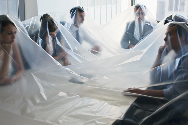Business people covered in plastic in conference room