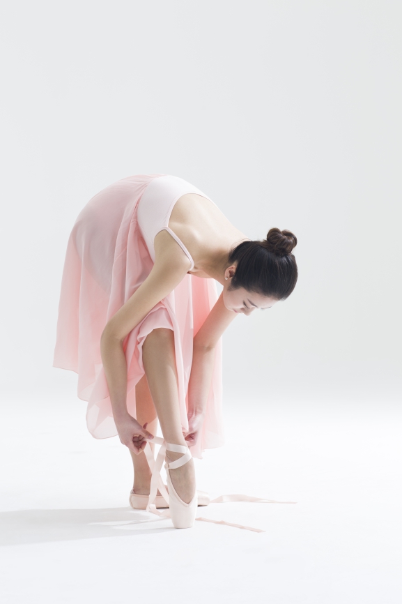 Chinese ballet dancer tying up pointe shoes