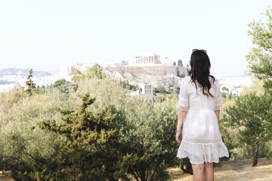 Athens, Greece. Woman looking at The Acropolis and Parthenon of Athens surrounded by olive trees from Areopagus Hill (Mars Hill) .