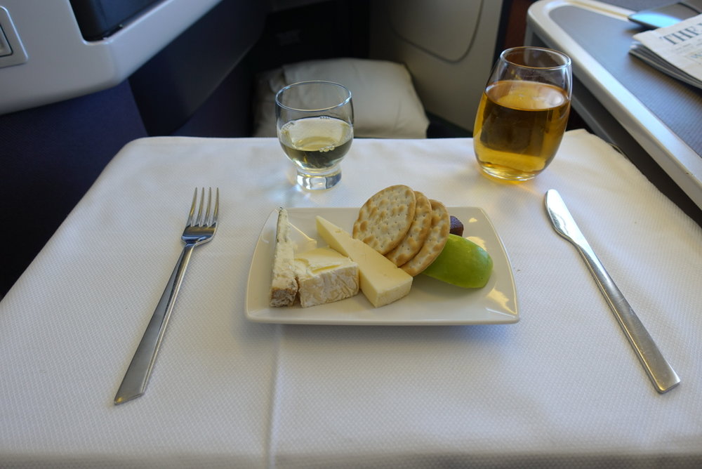  Cheese, crackers and dessert wine served on board CX418 from HKG --></noscript> ICN. “> Cheese, crackers and dessert wine served on board CX418 from HKG –> ICN.</p>
<p>So a few thoughts about Cathay Pacific, as a reference point to compare to Qatar Airways and British Airways later:</p>
<p><strong>Mobile app</strong></p>
<p>Cathay has improved its mobile app in recent years, but it is still a bit buggy. It has the usual features, such as profile/points accrual information, flight schedules, and the option to book flights through the app (it also wins a huge bonus from me for accepting Apple Pay).</p>
<p>The app also provides mobile boarding passes, which is becoming standard and is a feature I use almost every time I fly Cathay. Checking in via the app and downloading a boarding pass without having to speak to a single employee at the airport is true bliss.</p>
<p><strong>Lounges</strong></p>
<p>Frequent travelers have their favorite lounges, and CX has four of them at Hong Kong International Airport. The newest and flashiest is The Pier, near gate 60. It is absolutely huge, has CX’s famous noodle bar (dan dan noodles FTW), a long bar, hot and cold buffet, and a quaint little coffee stand. Almost all seats have electrical outlets and USB ports to charge devices.</p>
<p>The Wing is near immigration and is, therefore, the most popular. It also has a noodle bar and long bar but is often extremely crowded. The Bridge is probably my second favorite, and offers a lot of bread-based dishes like pizza, sandwiches, and paninis, while The Cabin is a darker lounge with fewer food options, but is well-known for its fruit smoothies.</p>
<p><img src=