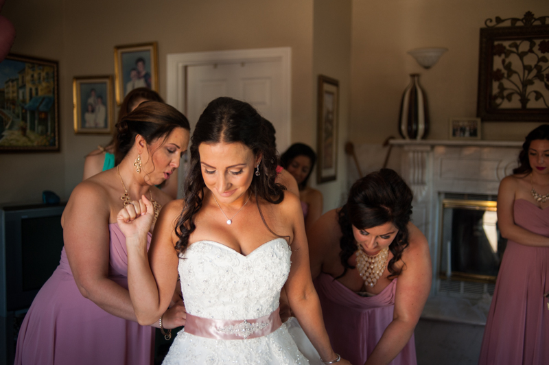 Bridesmaids helping Bride into wedding dress
