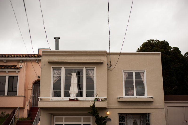 Wedding dress hanging in window of San Francisco home