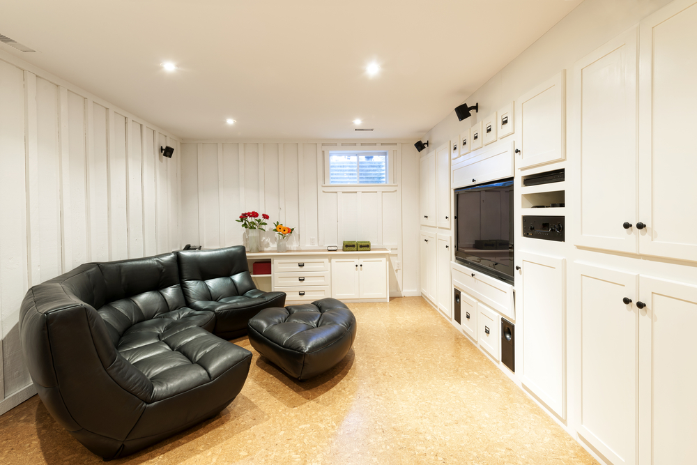 Finished basement with black leather furniture.