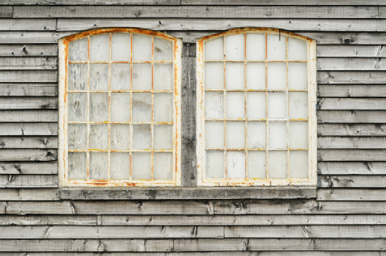 A pair of old, white window frames afflicted with rust.