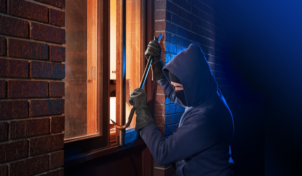 Burglar opening window to home
