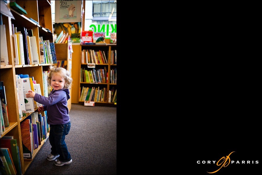 little girl choosing a book to read by seattle portrait photographer cory parris