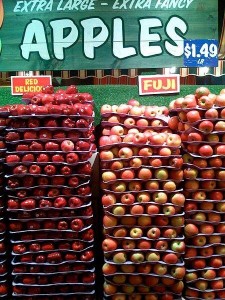 Manzanas Red delicious y las Fuji (derecha), bajo un cartel que dice “Manzanas extra grandes, extra lujosas” (Wikipedia)