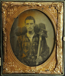 ca. 1860’s, [ambrotype portrait of a Confederate soldier wearing a plaid shirt and a holstered pistol. He carries a large bedroll, a percussion rifle and a kepi with the letters “4 SLG” for the 4th Sumter Light Guards] via Heritage Auctions