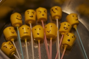 marshmallows covered in yellow candy melts decorated to look like lego faces